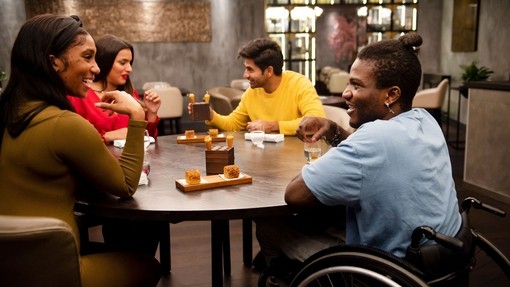 Group of friends, one wheelchair user, sat around a table