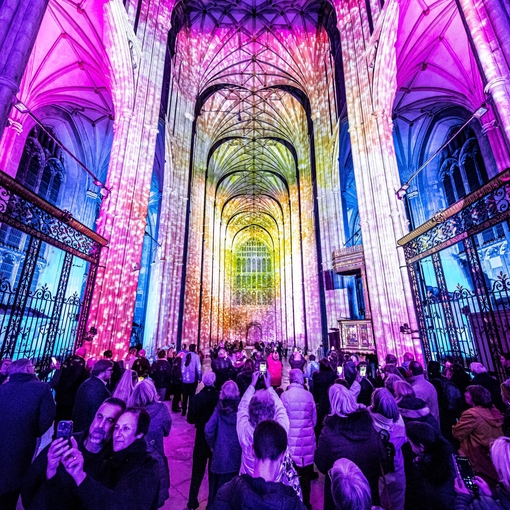 Group of people looking and photographing light show in a cathedral
