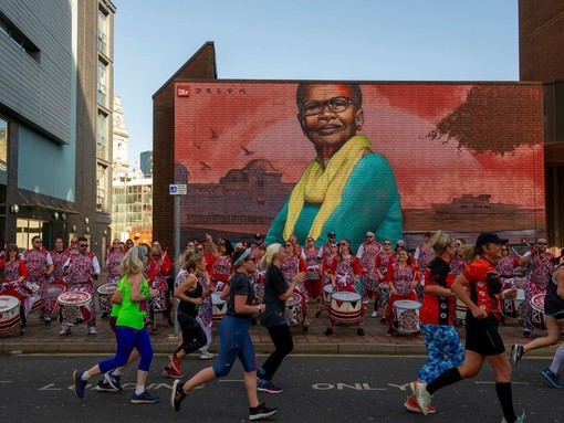 People running in front of a drumming band and colourful street art