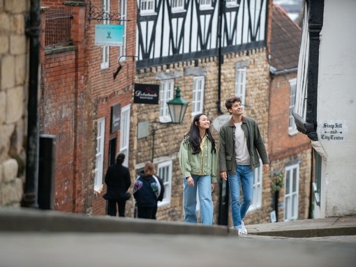 A woman and a man walk up a steep hill in a heritage City