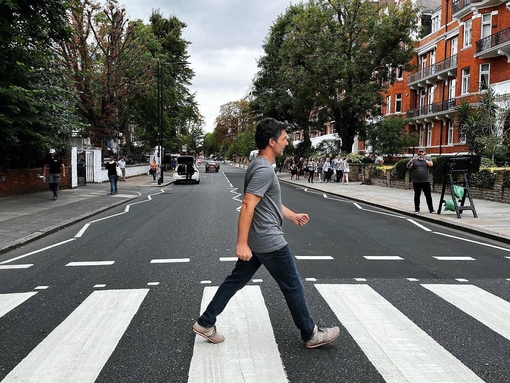A man crossing the road outside of Abbey Road Studios, a recreation of the famous album cover from The Beatles
