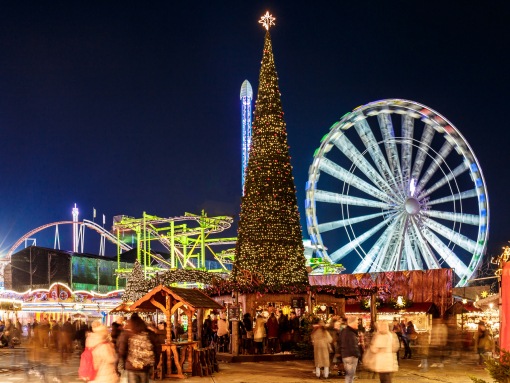 A night view to Hyde Park Winter Wonderland lit up with people milling around the market
