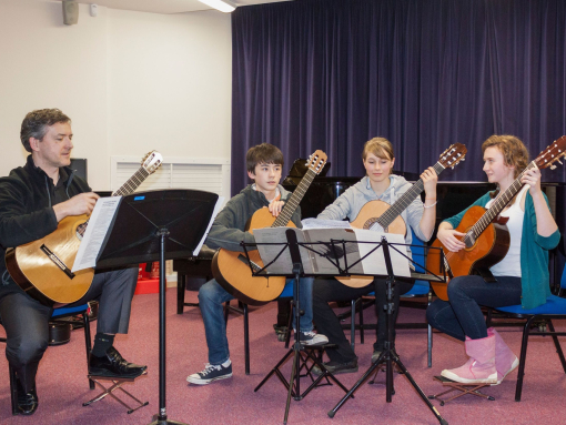 A group of people preparing to play guitars on stage as part of Oxford Music Festival