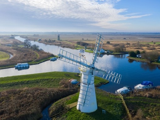 Aerial view of a windmill and surrounding pasture and canals