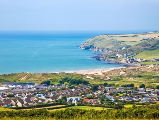 A clear view of a village from above and bay across mountains and out to the ocean