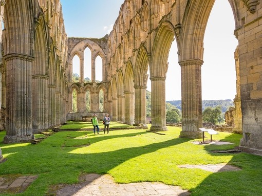 Two female friends in the central nave of a ruined abbey in the sunshine