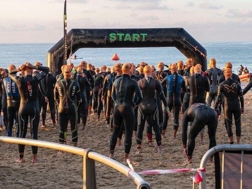 Competitors standing at the start line of a race wearing wetsuits.
