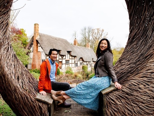 A young couple at Anne Hathaway's Cottage sitting on Tom Hare's 'The Moon Seat', Stratford-upon-Avon, Warwickshire, England