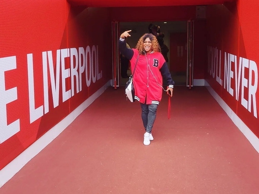 A woman posing while on a stadium tour of Anfield, Liverpool.