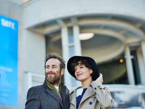 A man and woman standing outside the entrance of a gallery
