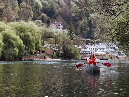 A woman in a canoe with hills and buildings behind