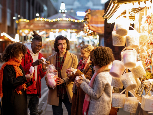 Group of young friends sharing a bag of cotton candy at the Christmas market