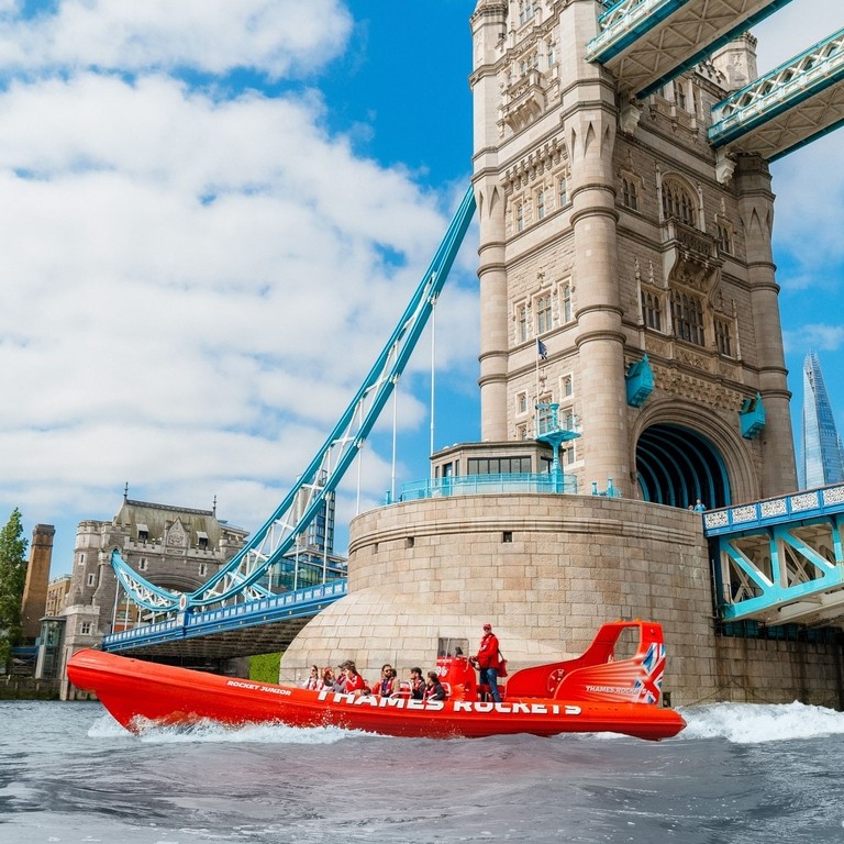 A speedboat with tourists zipping past Tower Bridge