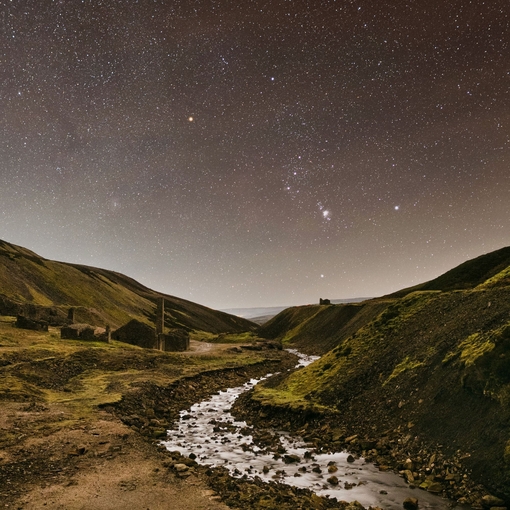 A stream winding through the mountains under a starry sky.