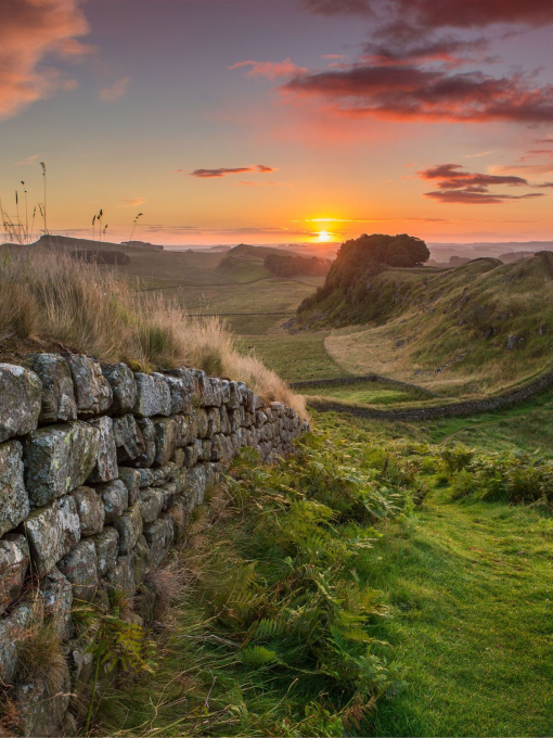 View along long stone wall over the fields at sunset