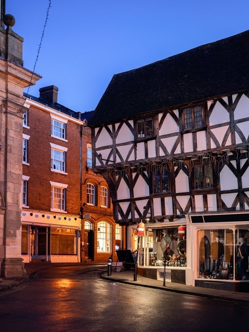 Black and white tudor building in a town centre at dusk
