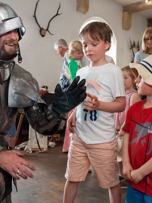A performer in armor posing with two children at Bolton Castle in Yorkshire