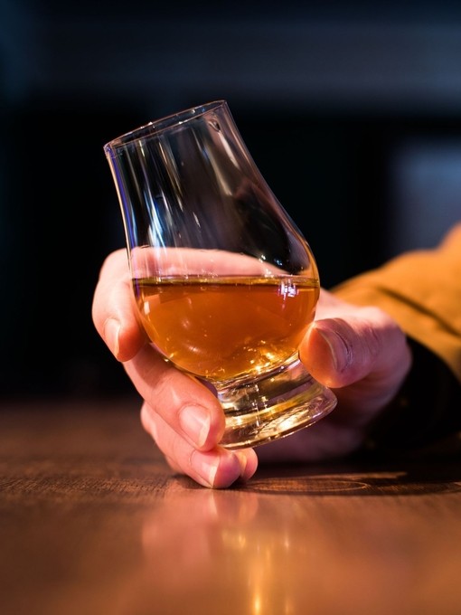 Close up shot of a hand holding a whisky glass