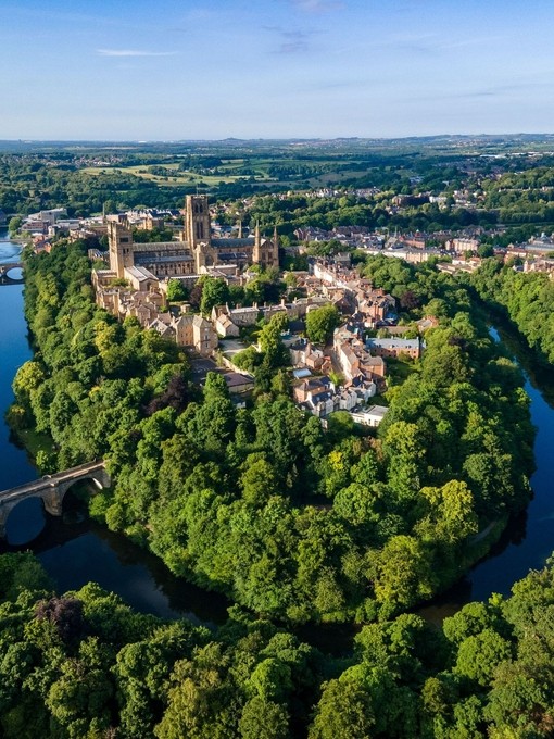 An elevated view of a Cathedral set amongst trees and a river