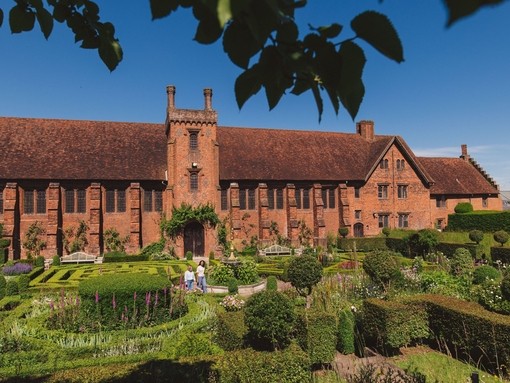 Two women walk through the gardens of a heritage house