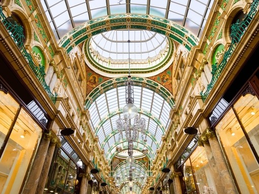 A majestic shopping arcade with ornate domed glass ceiling.