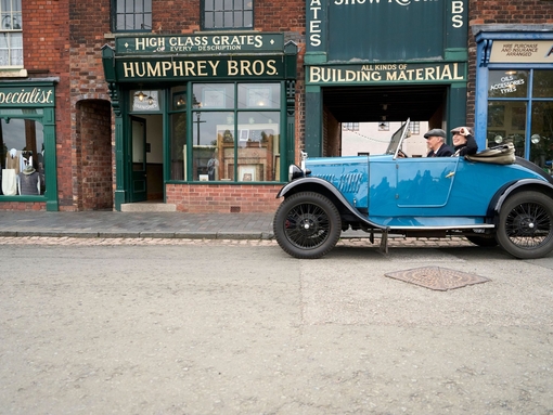 Two people inside a vintage car at a living museum