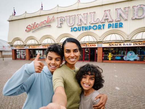 A mother and two sons stand outside an amusement park