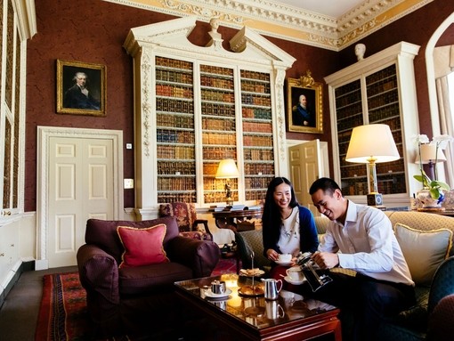 An asian couple, sitting on a sofa, having afternoon tea