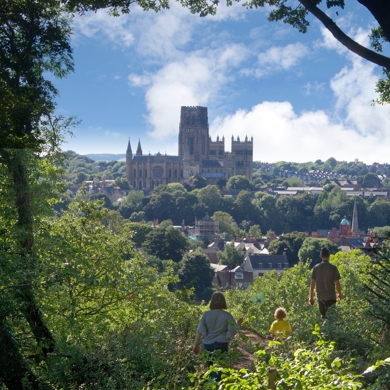 Family walking on a hill top looking down on to Durham Cathedral