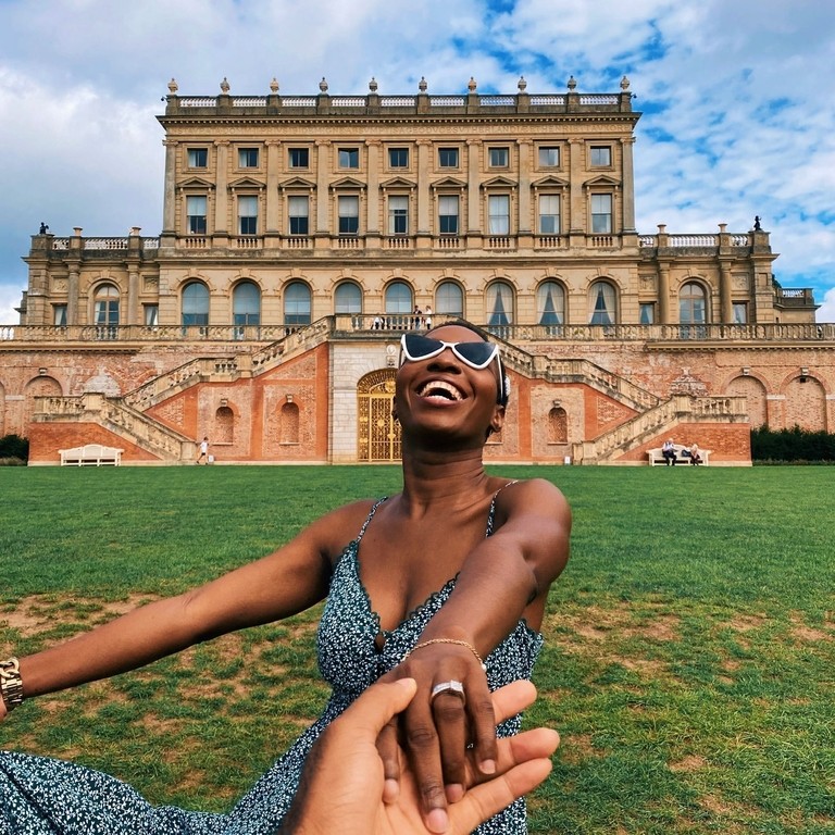 Smiling woman, wearing sunglasses and sundress, outside Cliveden Hotel